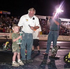 Royce Miller awards the Big Wheel winner's trophy to the rambunctious Timmy Walker! 7-08-00 by Tim Pratt